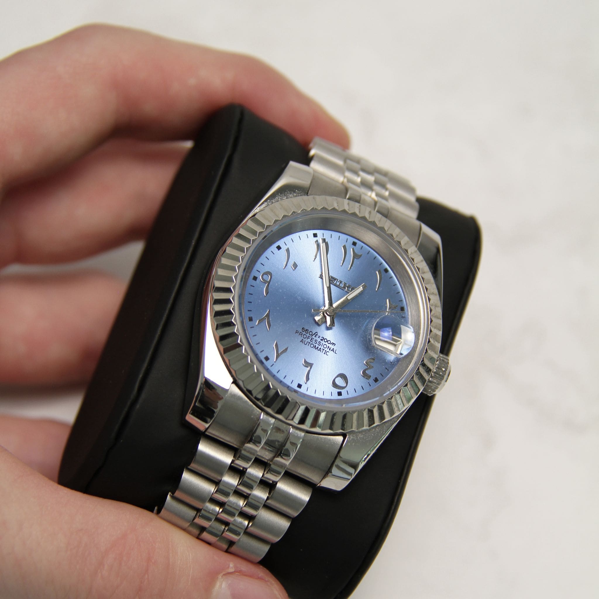 Montre Seiko mod datejust arabic bleu vu de face sur coussin.