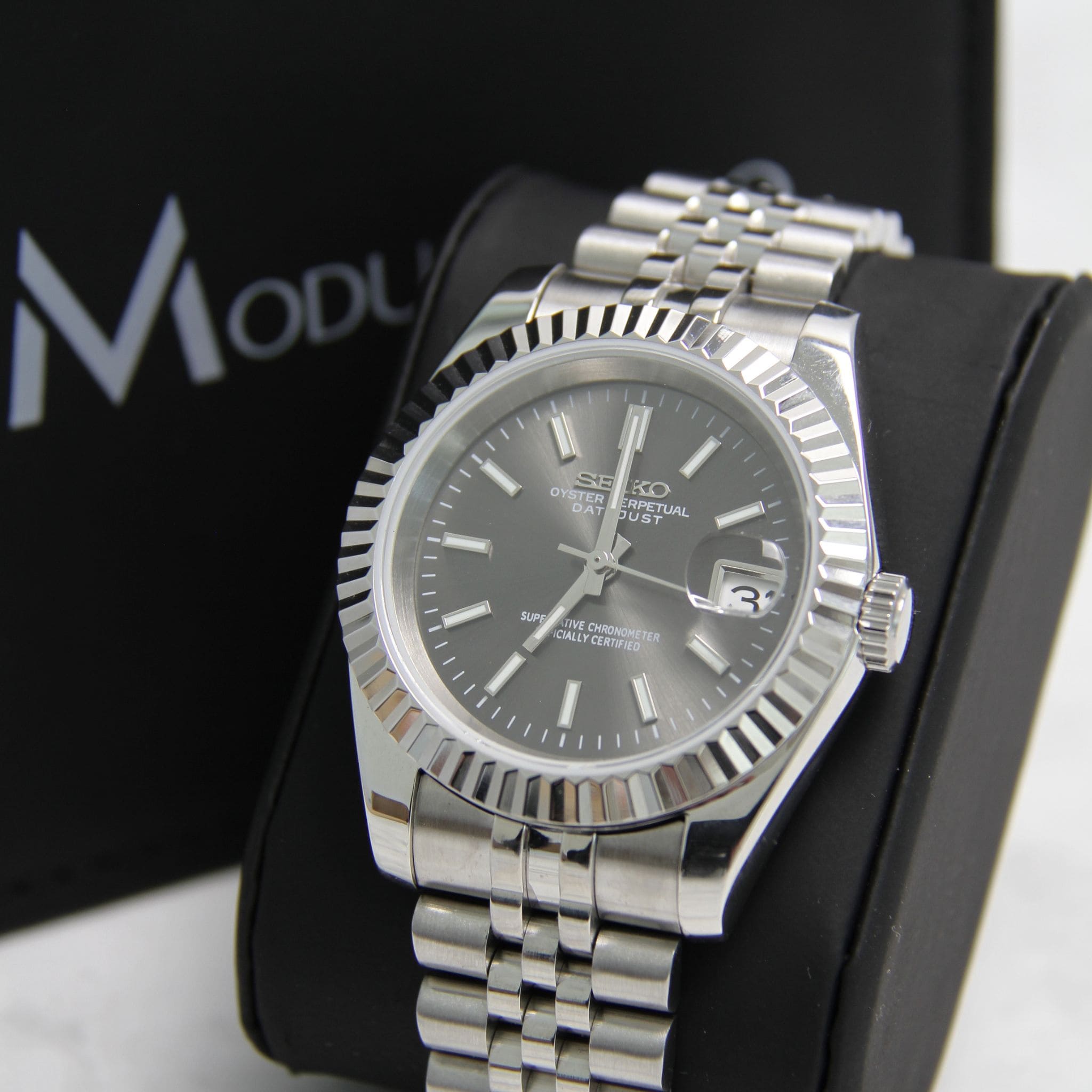 Montre Seiko mod datejust gris vu de face sur coussin