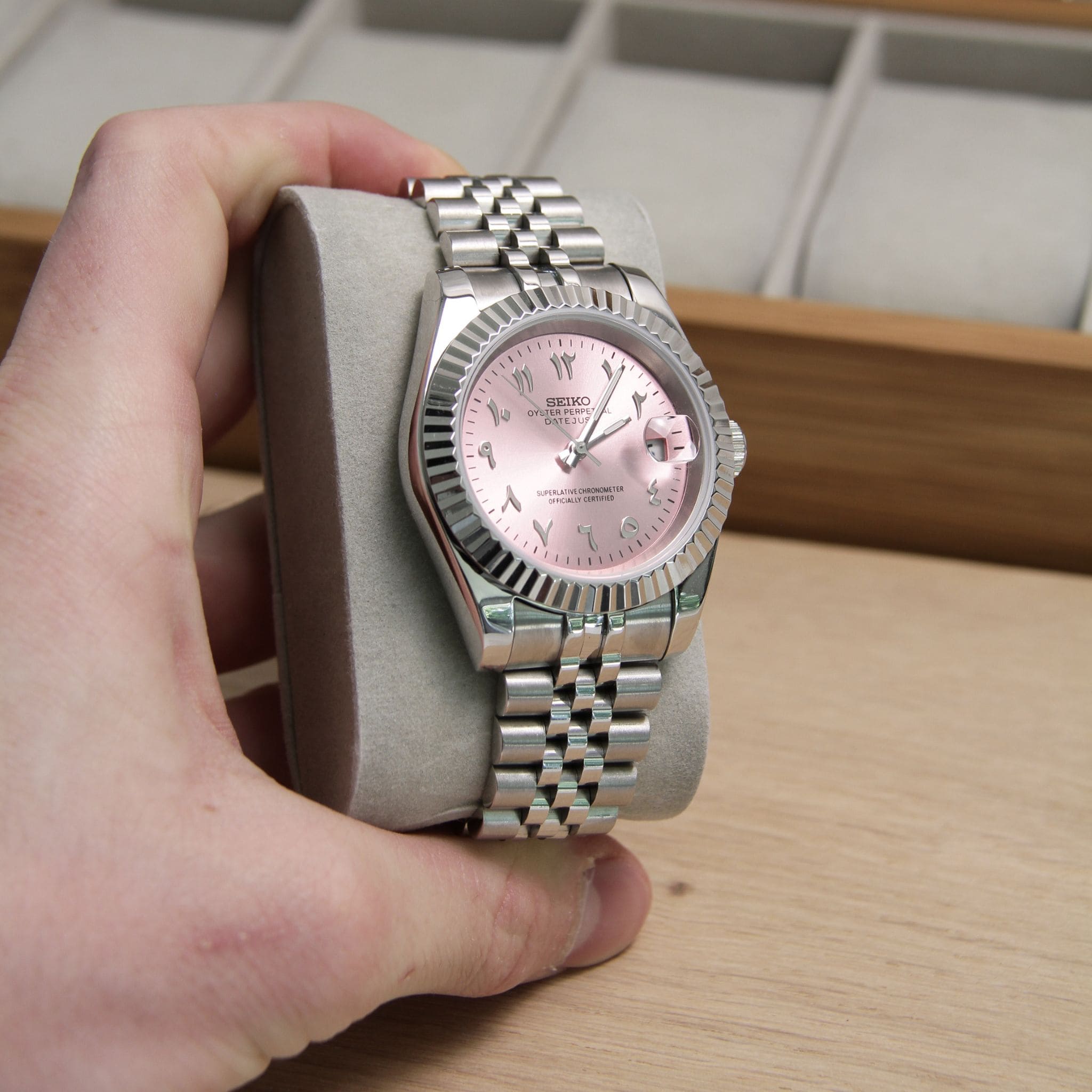 Montre Seiko mod datejust rose vu de face sur coussin