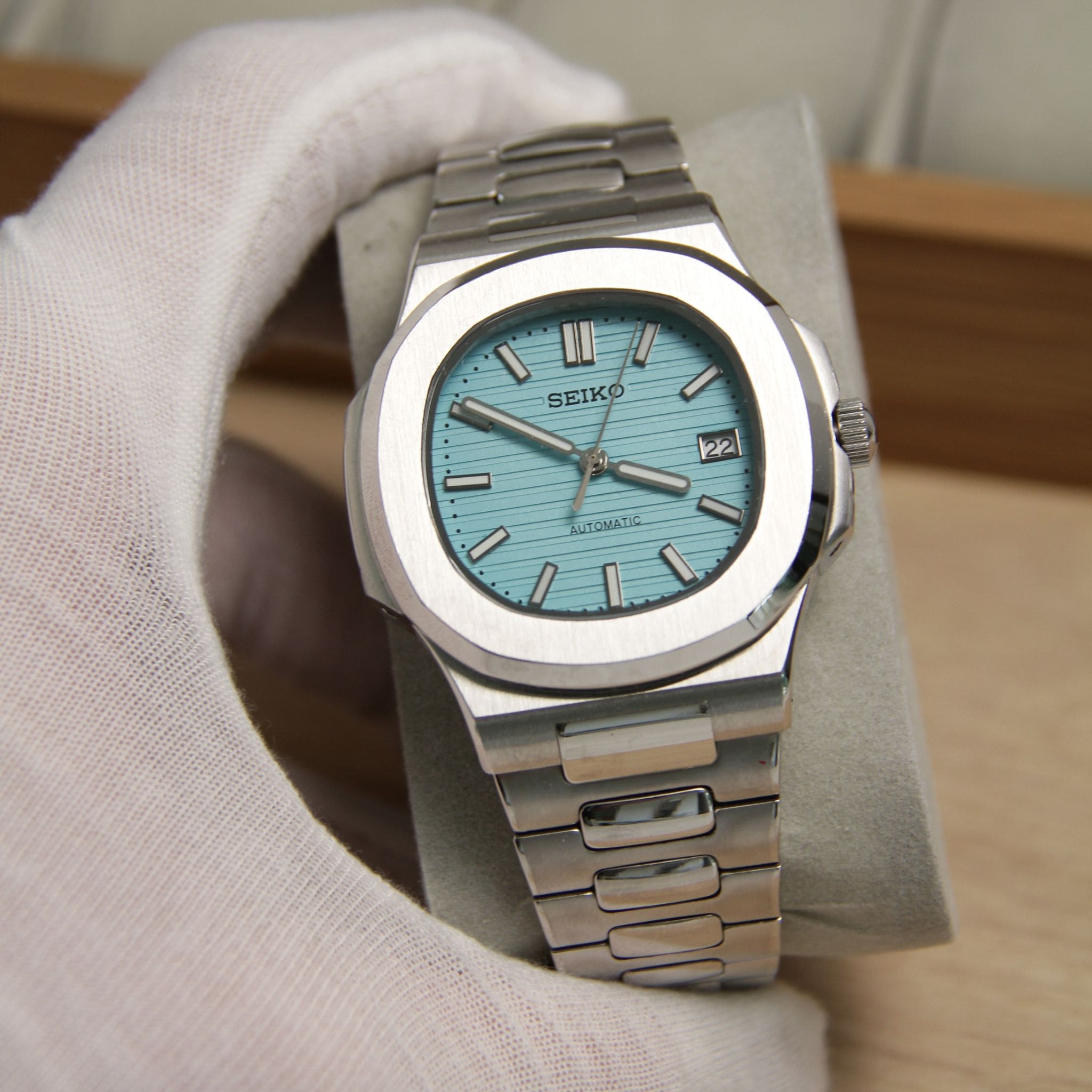 Montre Seiko mod nautilus Tiffany bleu ciel vu de face sur coussin.