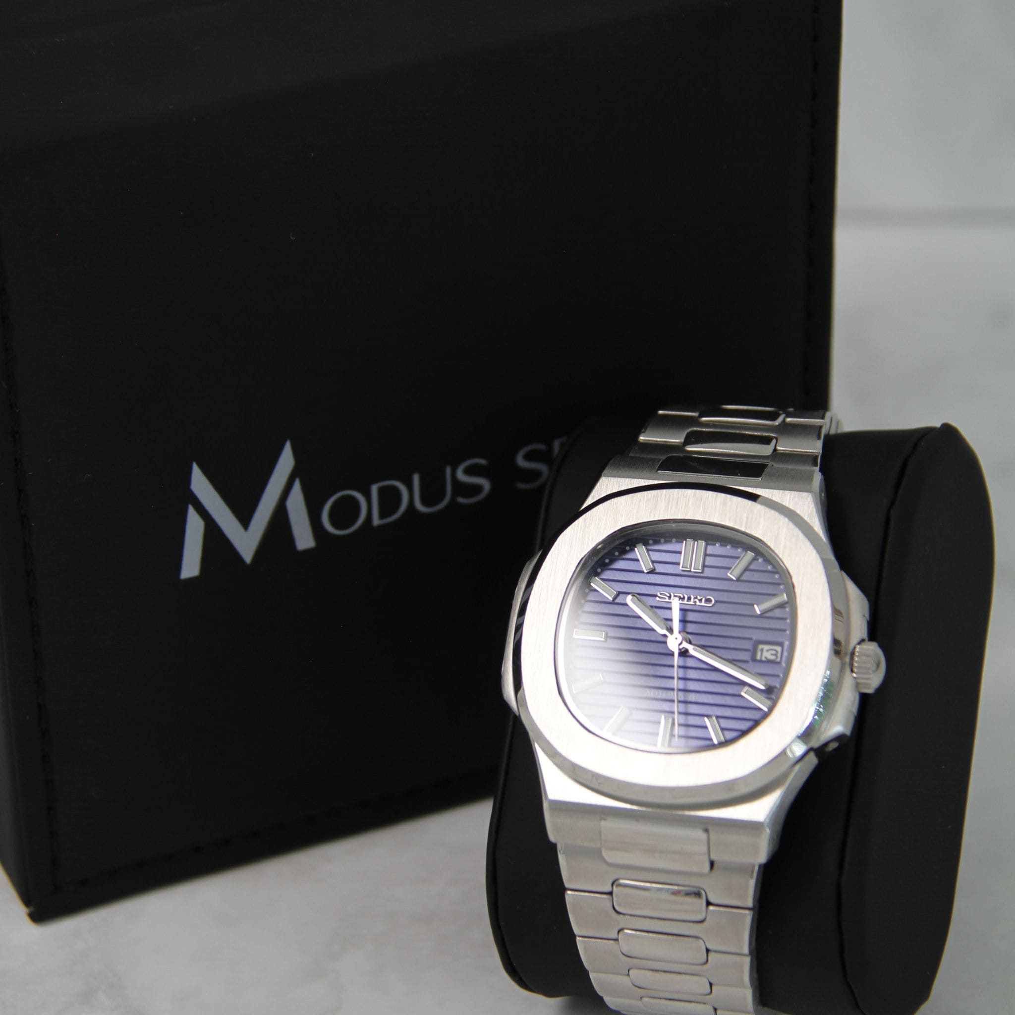 Montre Seiko Mod nautilus bleu marine sur coussin noir avec écrin en arrière plan