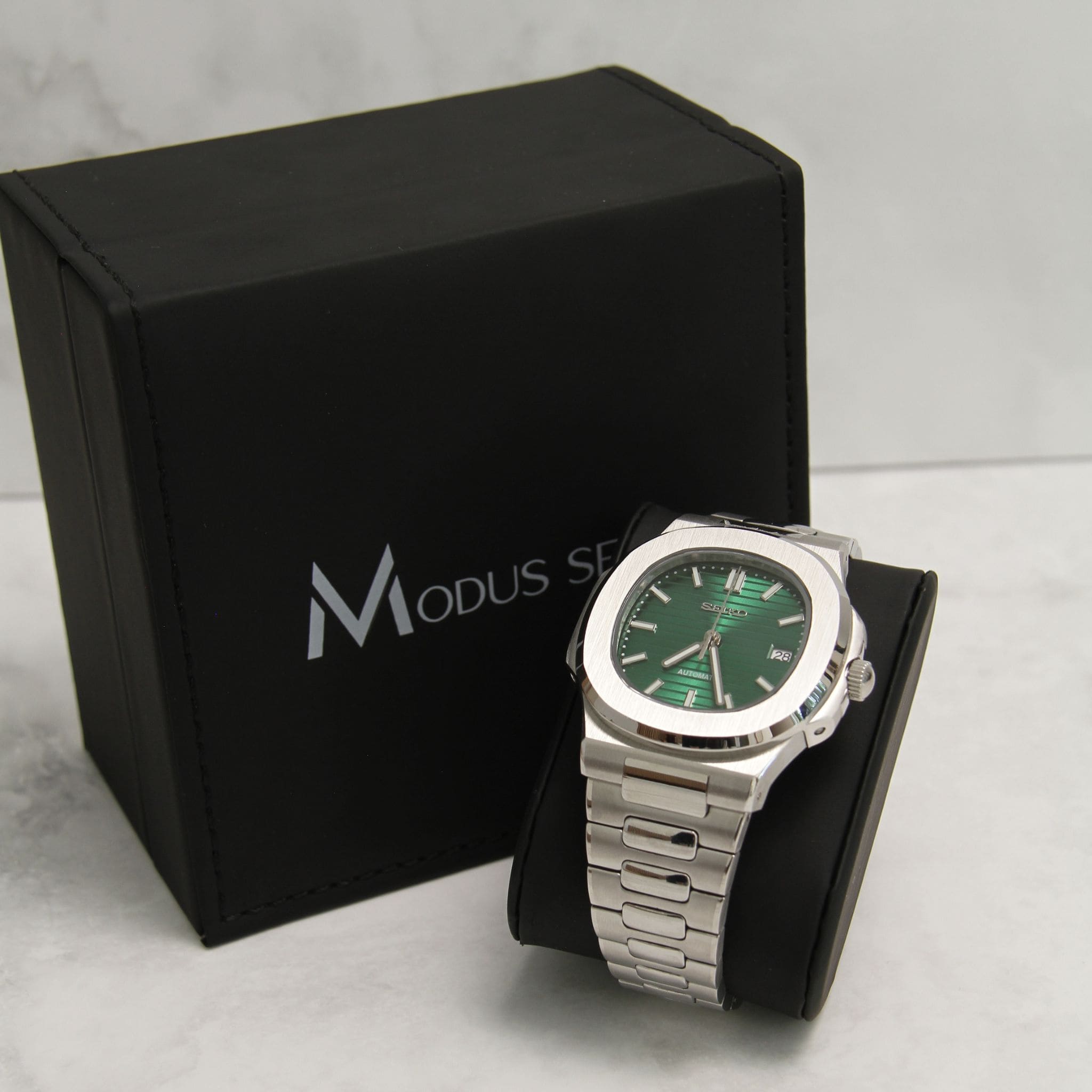 Montre Seiko Mod nautilus vert sur coussin noir avec écrin en arrière plan