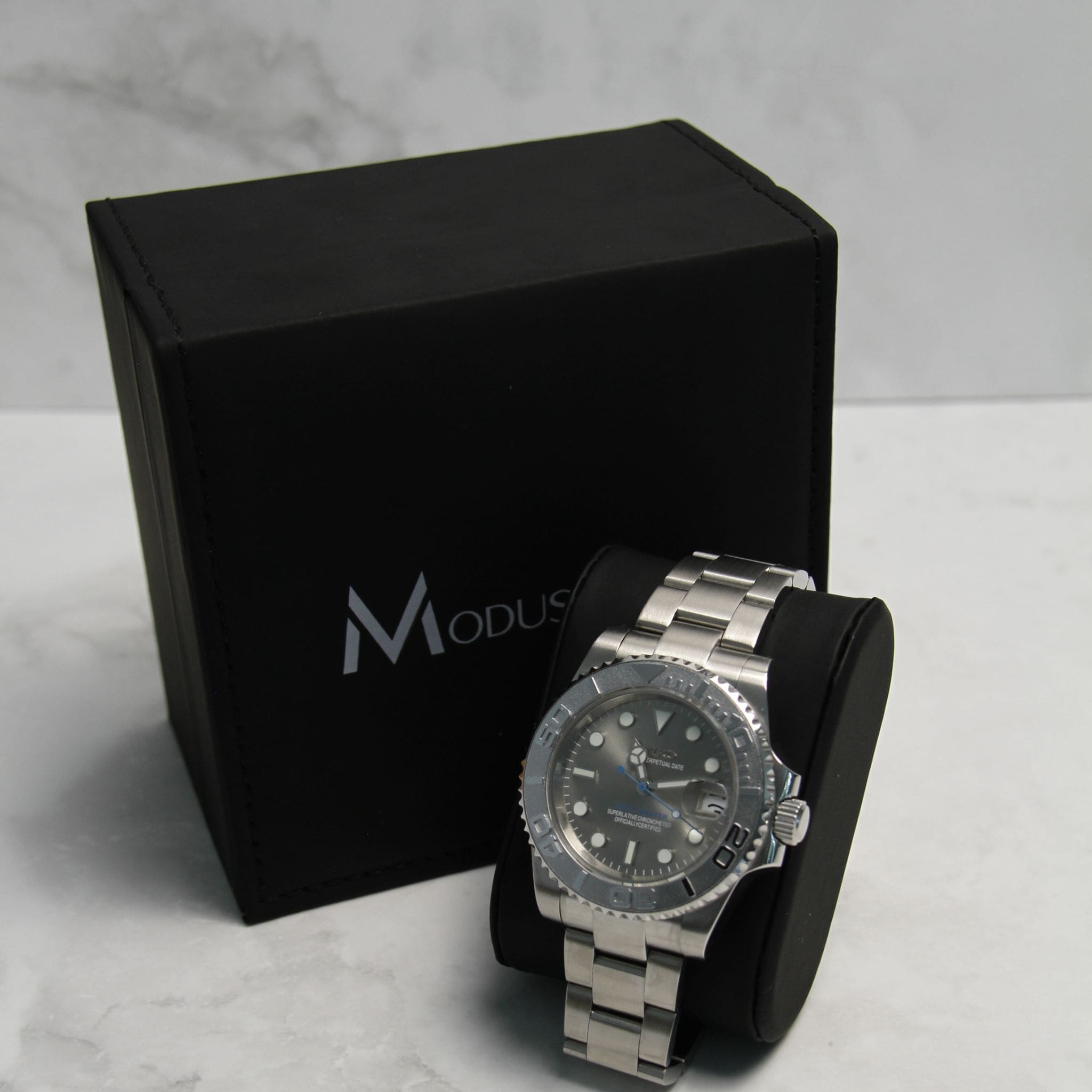 Montre Seiko Mod yachtmaster bleu gris sur coussin noir avec écrin en arrière plan