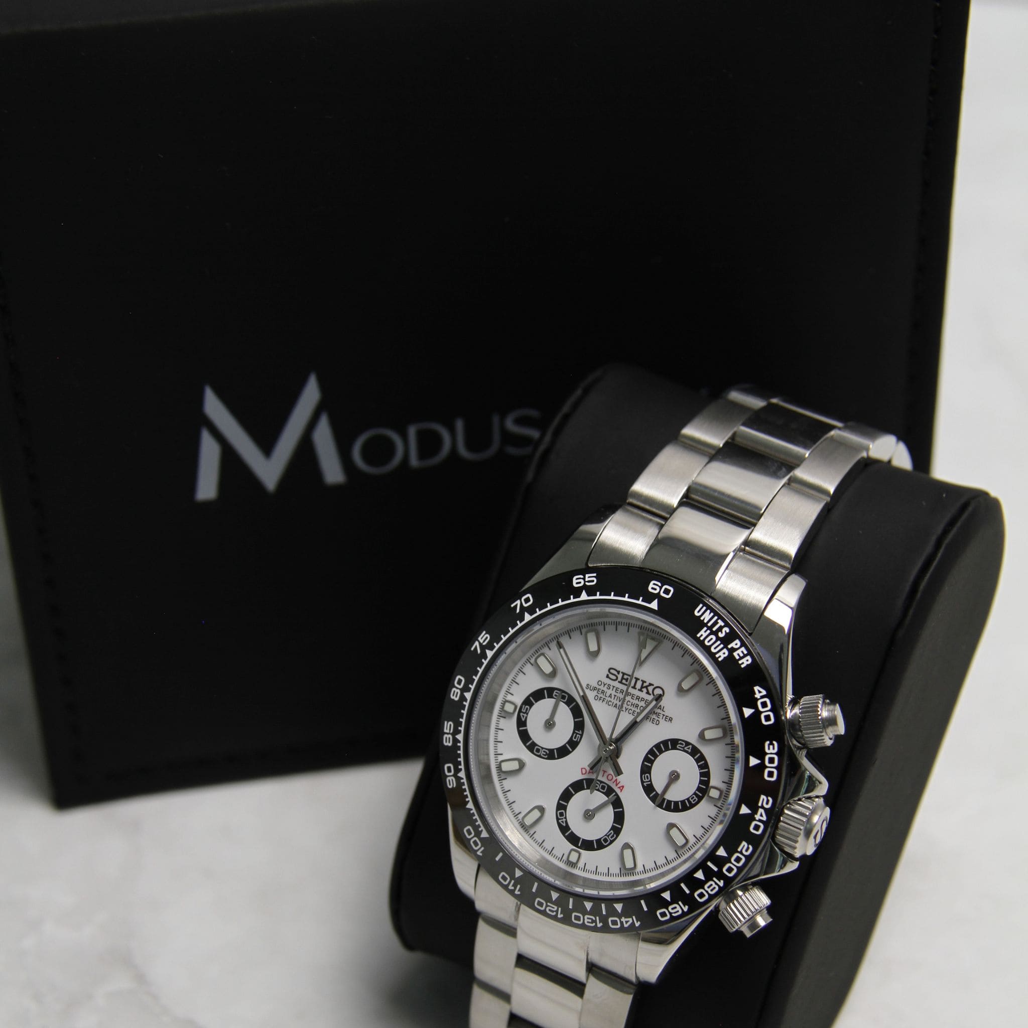 Montre Seiko Mod daytona panda noir blanc sur coussin noir avec écrin en arrière plan