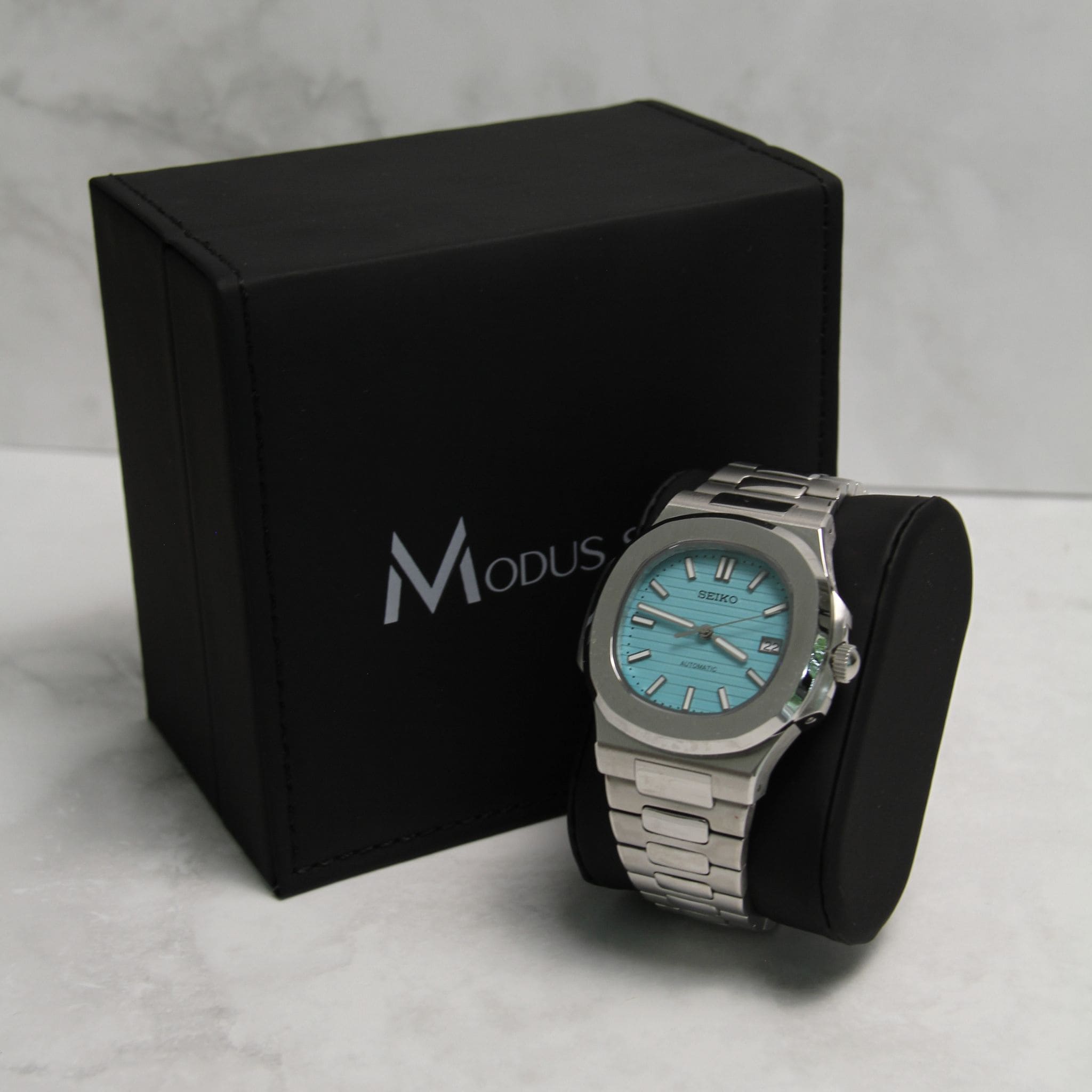 Montre Seiko Mod nautilus Tiffany Bleu ciel sur coussin noir avec écrin en arrière plan
