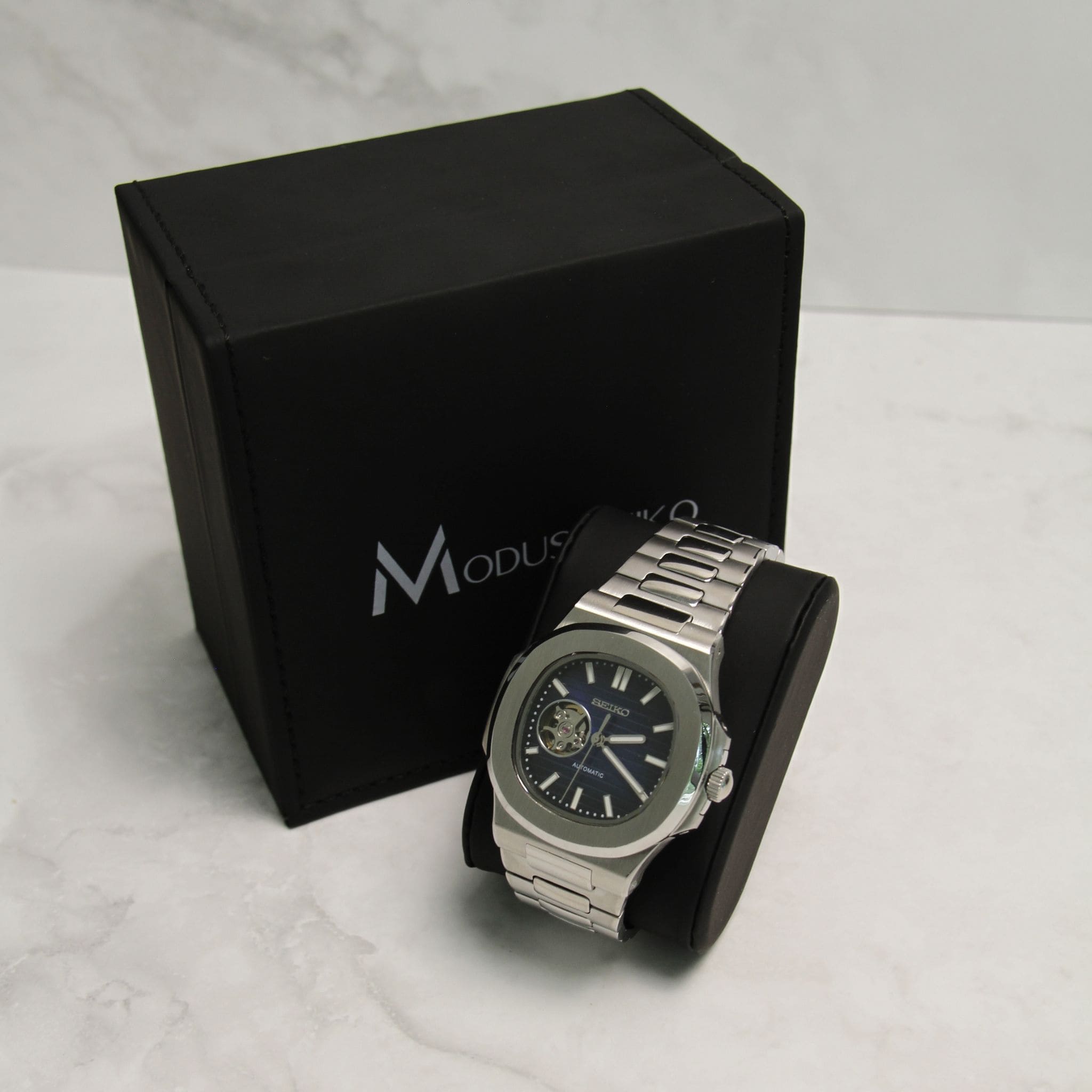 Montre Seiko Mod nautilus bleu squelette cœur ouvert sur coussin noir avec écrin en arrière plan