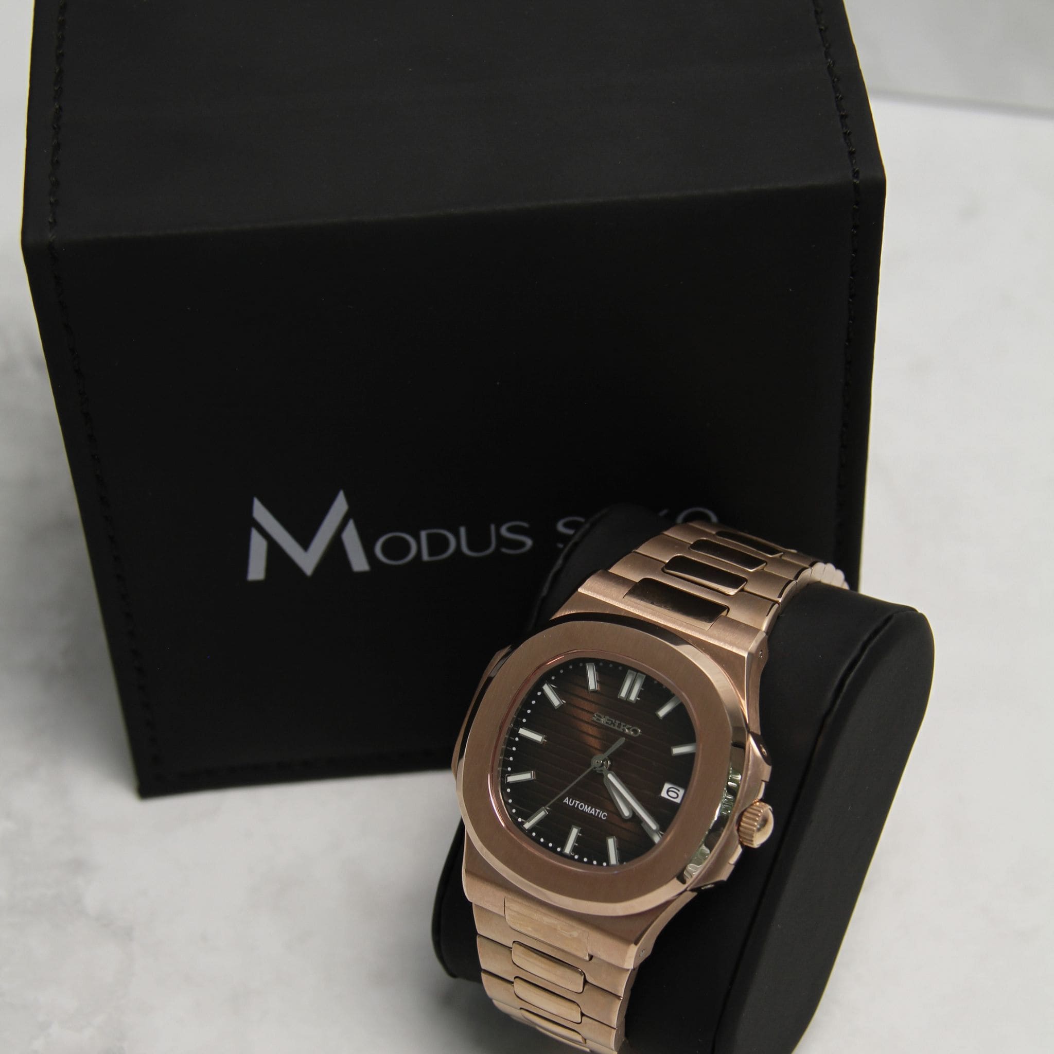 Montre Seiko Mod nautilus Marron or rose sur coussin noir avec écrin en arrière plan