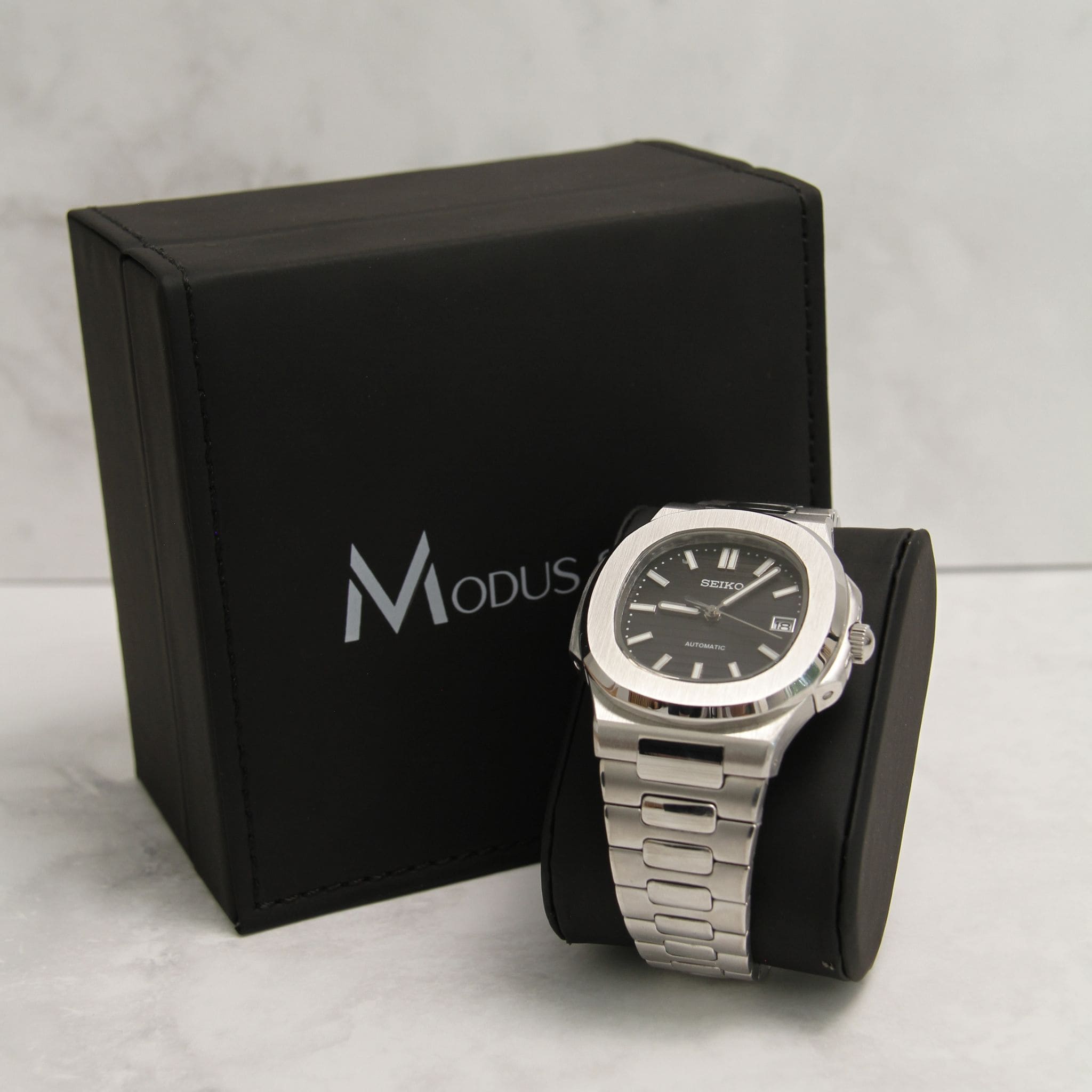 Montre Seiko Mod nautilus noir sur coussin noir avec écrin en arrière plan